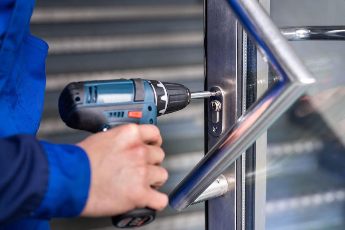Commercial locksmith repairing the lock on an office door.