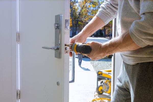 A residential locksmith service provider installing a new door lock.