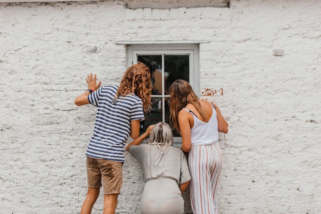People peeking through a window after being locked out of the house