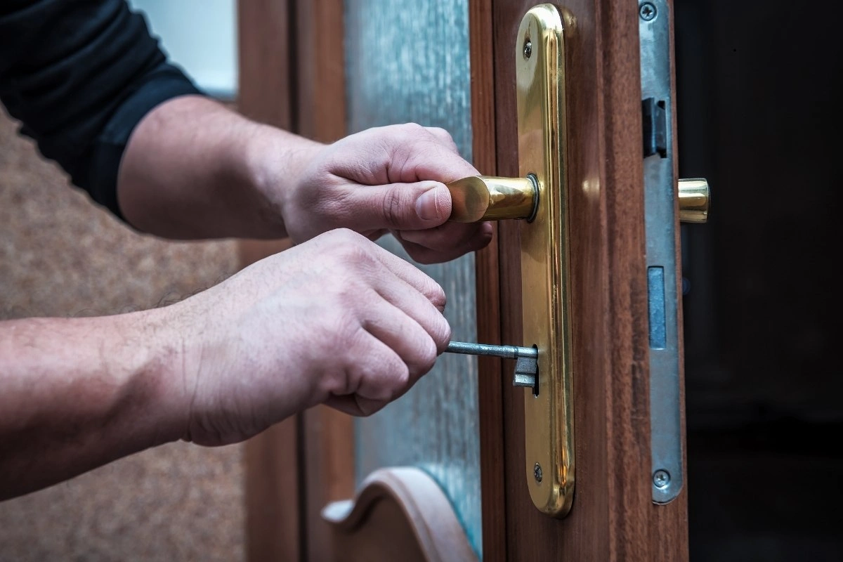 Homeowner inspecting worn front door lock.