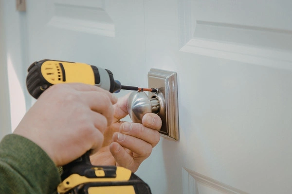 Locksmith replacing residential door lock.